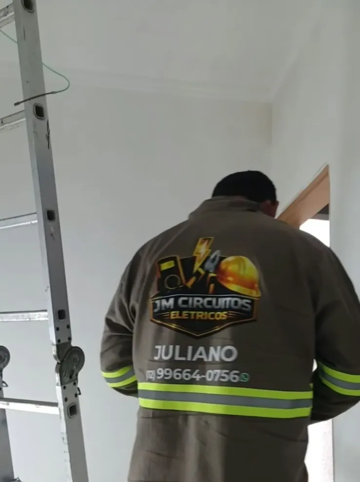 Juliano, da equipe JM, de costas com o uniforme da empresa, o logo e o telefone