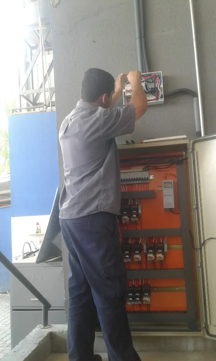 Eletricista da JM ligando a caixa de entrada de um quadro de comando.